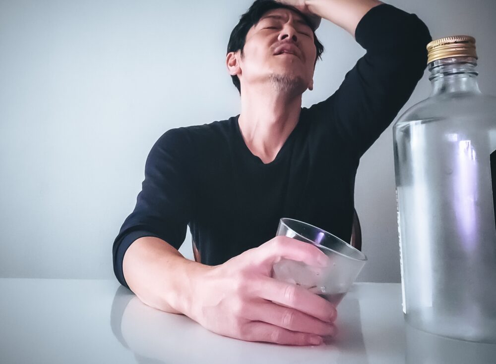 お酒片手に悩む男性